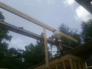 Carpenter setting a ridge beam over a new addition frame — Ice Dam Removal by Roofing Brothers in Only