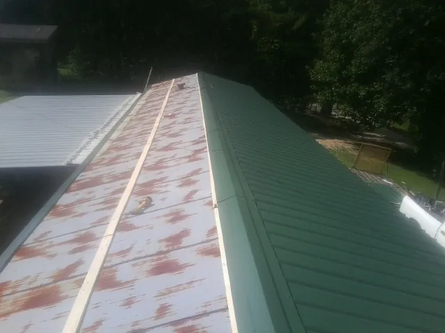 Old rusted panels beside newly installed green metal roofing — Wind Damage Roof Repair by Roofing Brothers in Only
