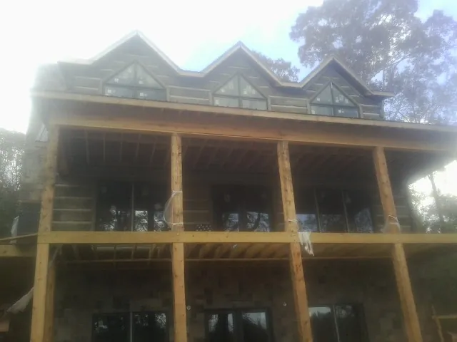 Dormers and porch framing on a large log home under construction — Roof Coating work by our crew in Only