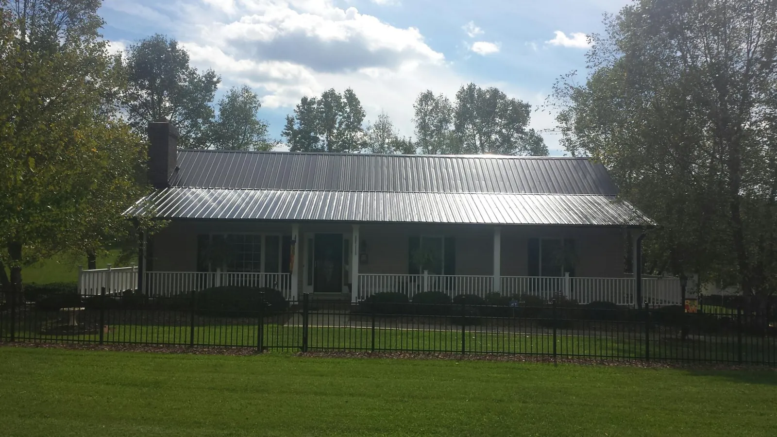 Gray metal roof on a brick ranch with a full width front porch — Gutter Guard Installation work by our crew in Only