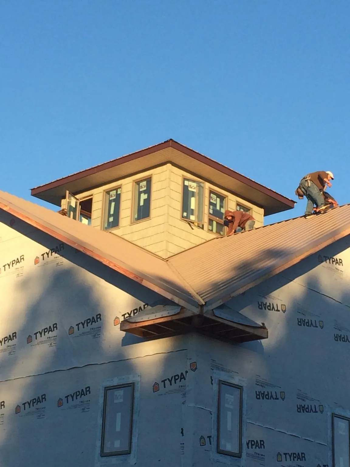 Roofers working around a rooftop cupola on a new metal roof at sunset — Roof Waterproofing in Only by Roofing Brothers